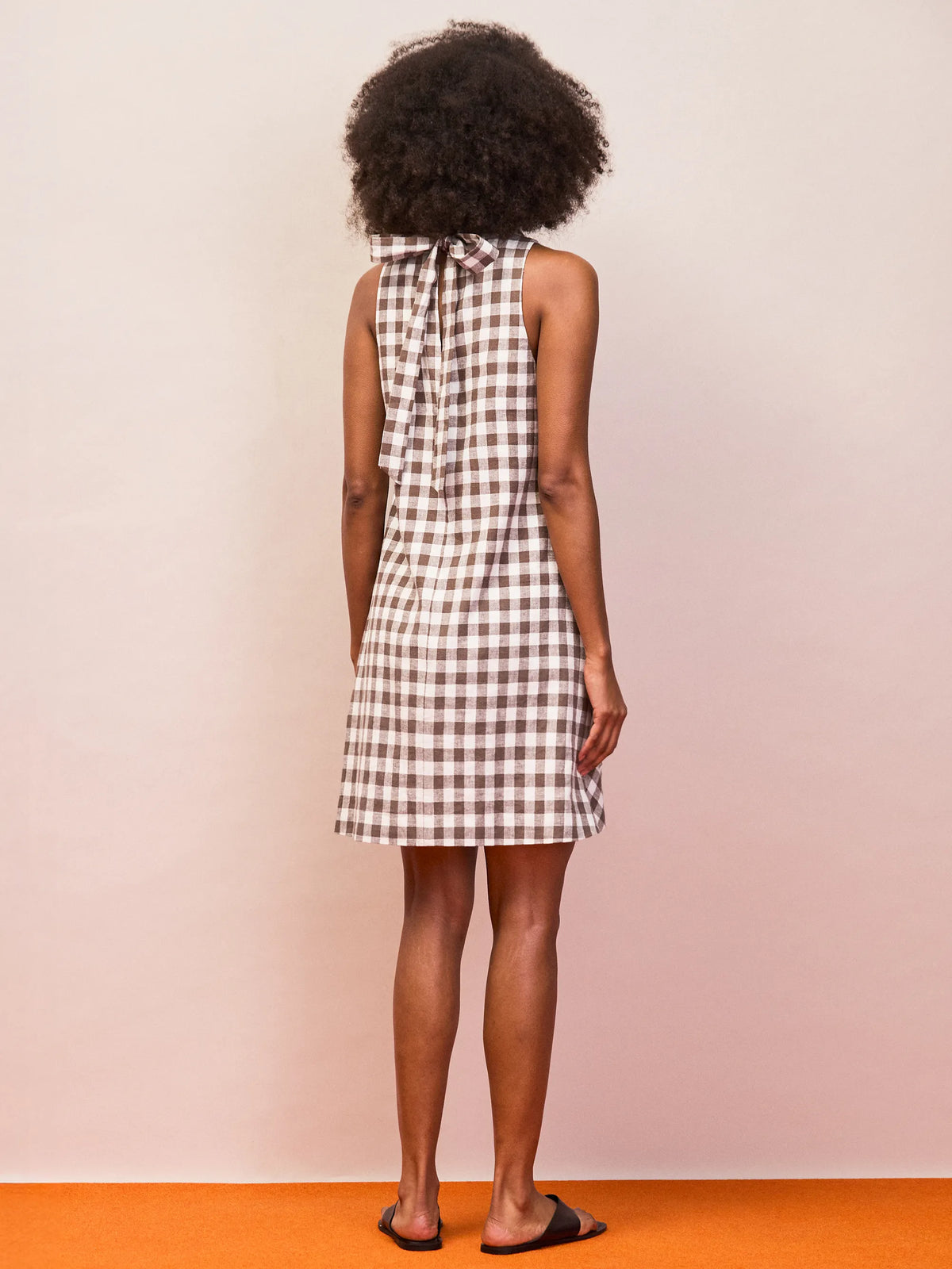 Sleeveless brown gingham mini dress with cowl neck and open tie back