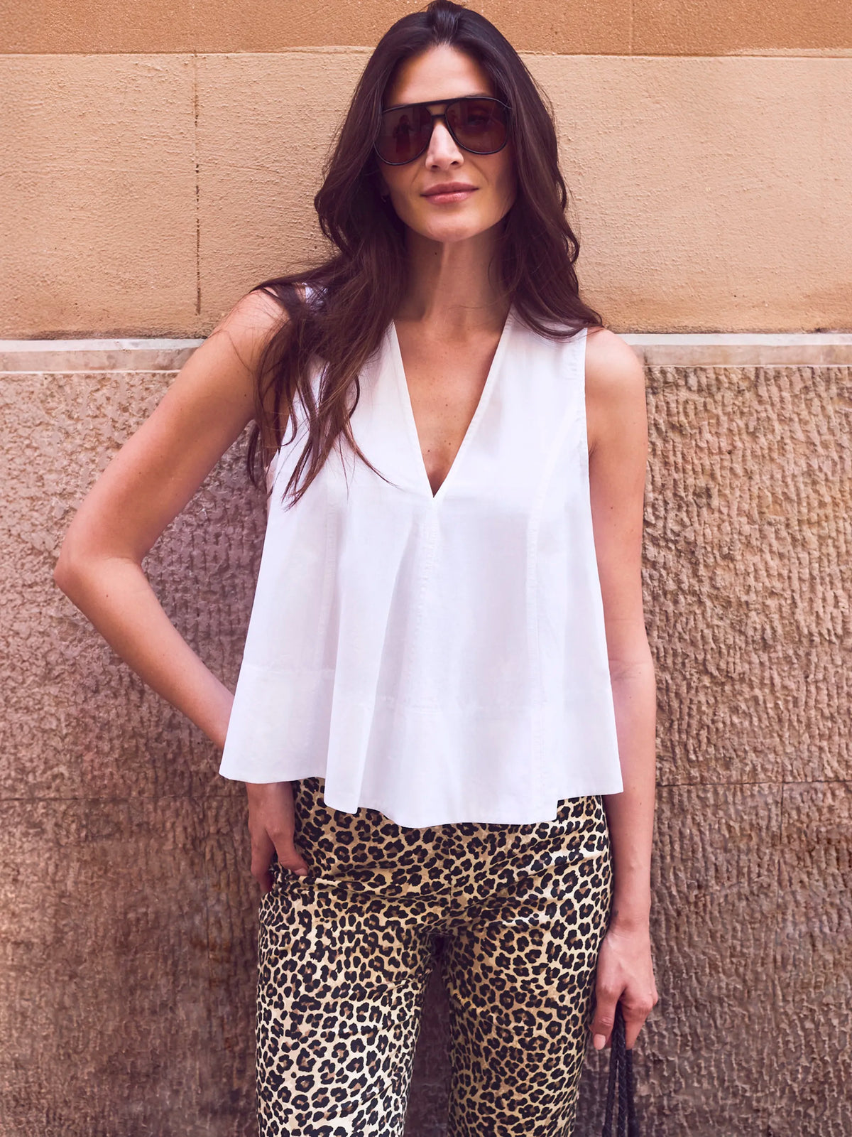 White sleeveless swing top with deep V-neckline, flared silhouette and relaxed fit.